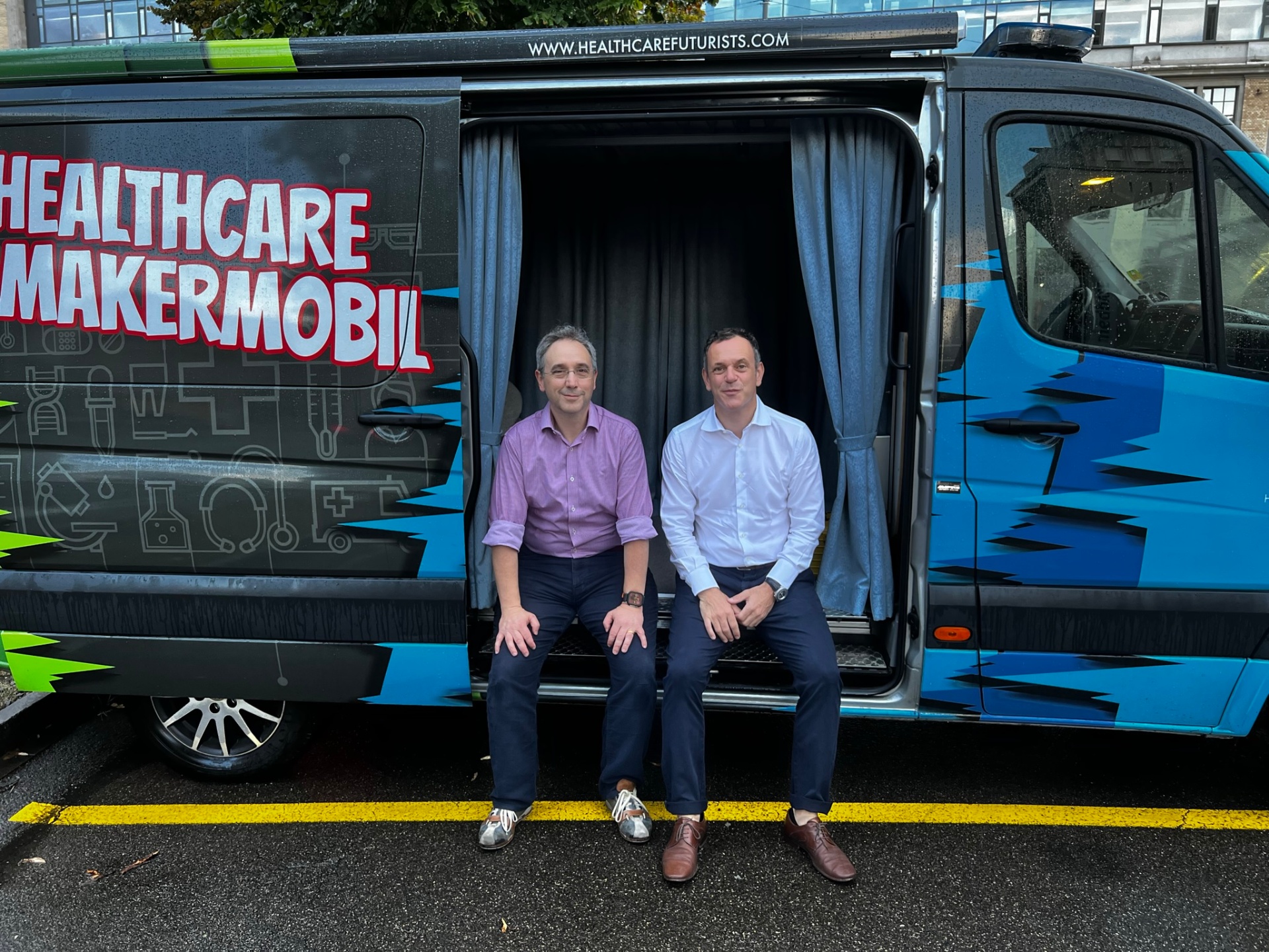 Two men sitting at entrance of Healthcare Maker Mobil van